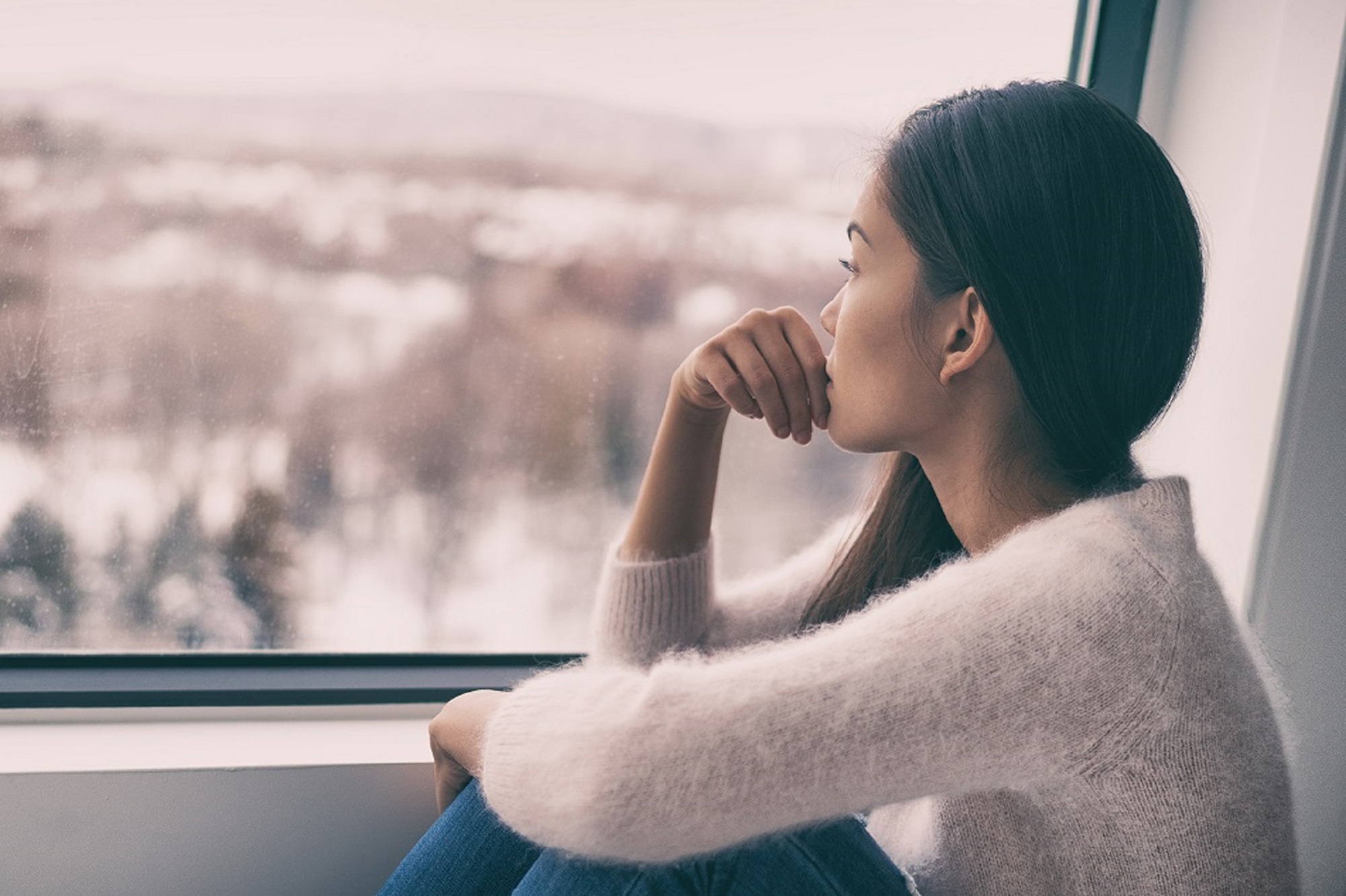 Sad women sitting near window alone