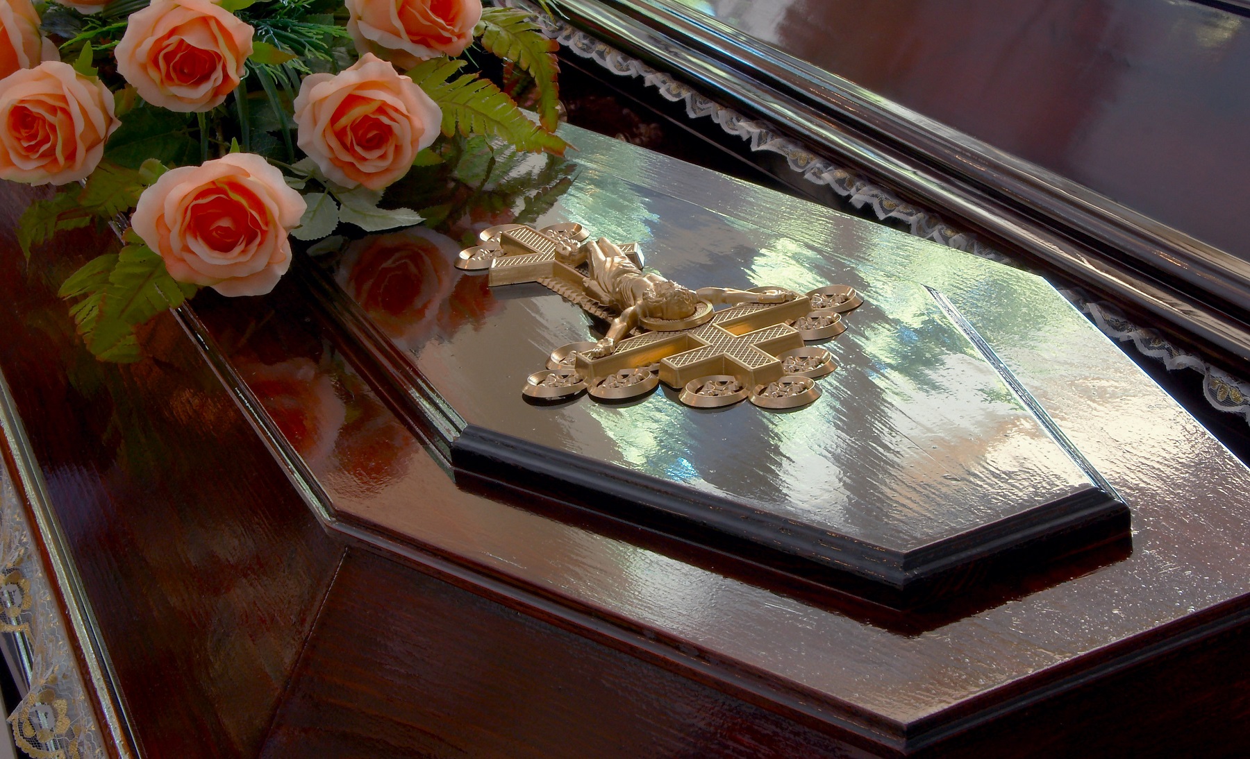 Dark wooden coffin with Jesus crucifix and roses