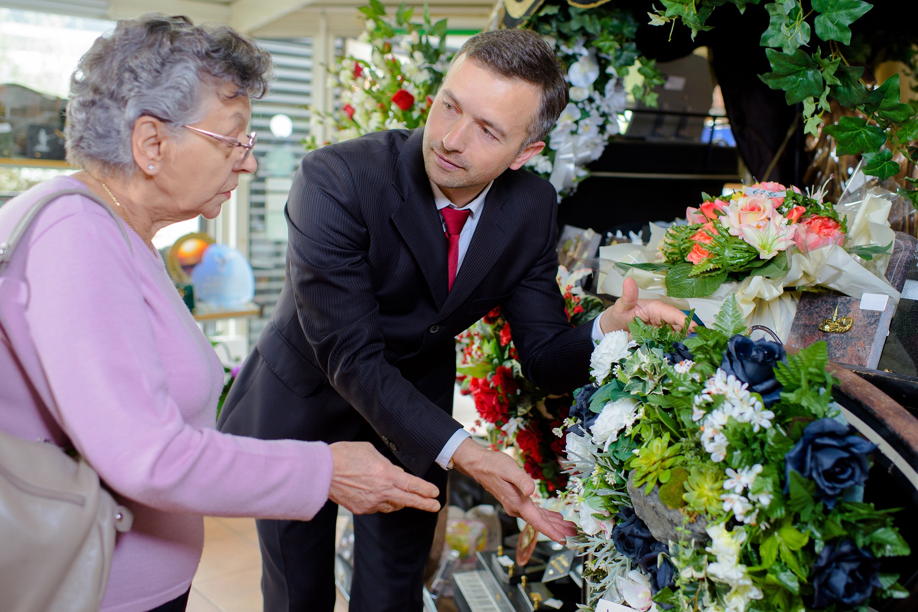 woman choosing flowers with help of funeral director